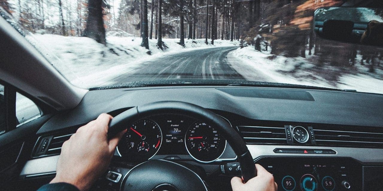 a man holds the wheel with both hands on a winter day