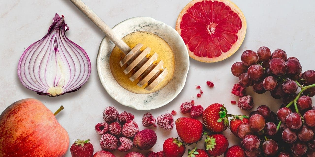 apple, berries, grapes and citrus also honey with dipper in an appetizer plate next to slice onion