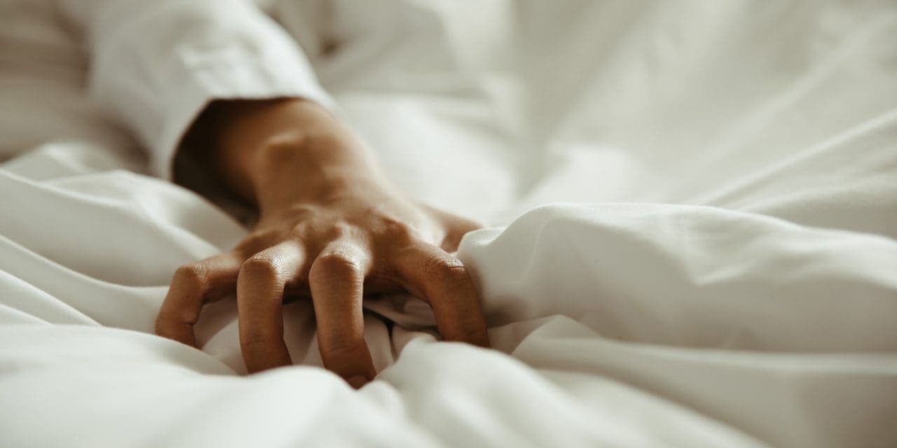 close up hand of female pulling white sheets